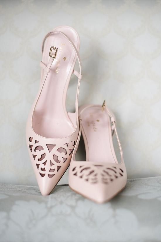 A pair of pink high-heeled shoes sitting on top of a bed