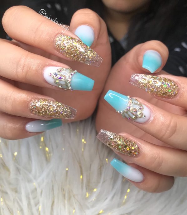 A woman holding a pair of blue and gold Quinceanera themed nails