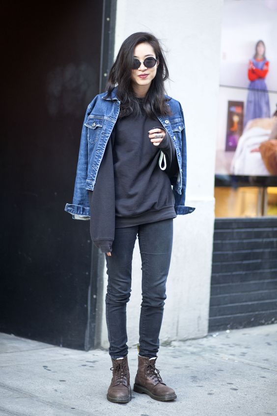 Quinceanera: A woman wearing doc martens boots stands on the sidewalk in a denim jacket
