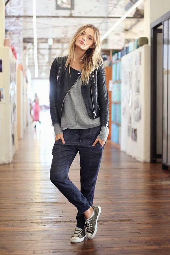 A cute tomboy standing in a Quinceanera hallway wearing a leather jacket and jeans