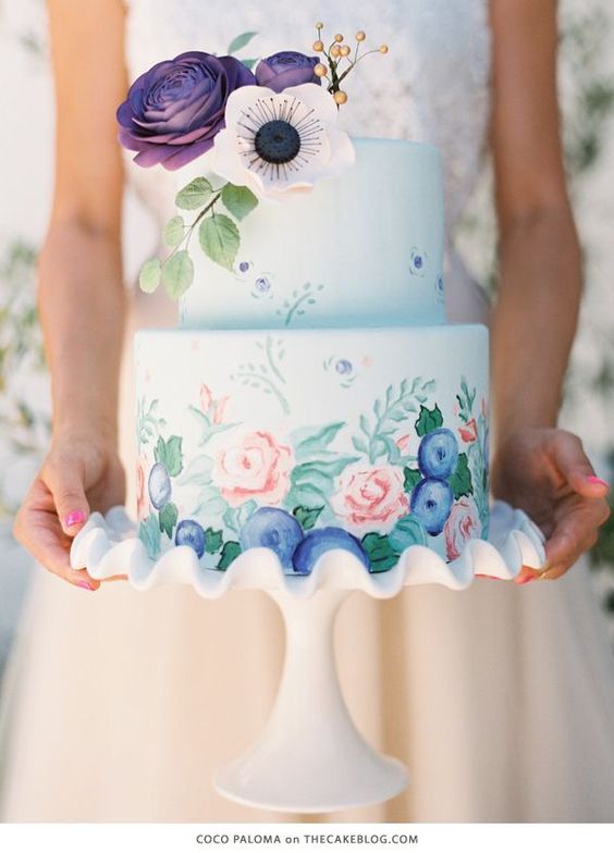 Quinceanera blue flower watercolor cake. A woman holding a cake with flowers on it.