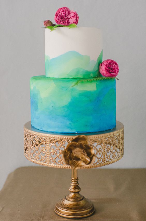 a Quinceanera themed blue and green watercolor cake with pink flowers on top