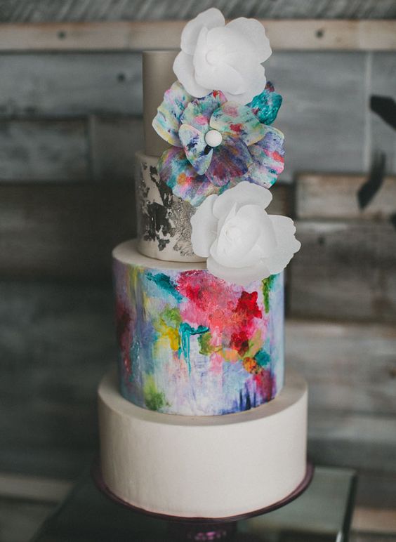 A vibrant Quinceanera cake with artful decorations and multicolored flowers on top