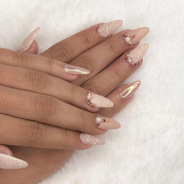 A woman's hand with a pink and gold manicure for a Quinceanera