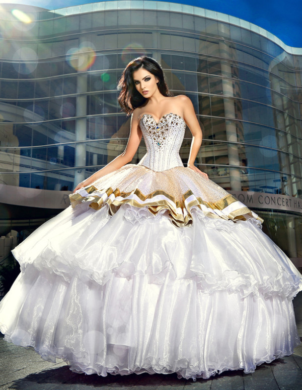 A Quinceanera celebration at the Renée and Henry Segerstrom Concert Hall. A beautiful woman wearing a white and gold dress stands in front of the building.