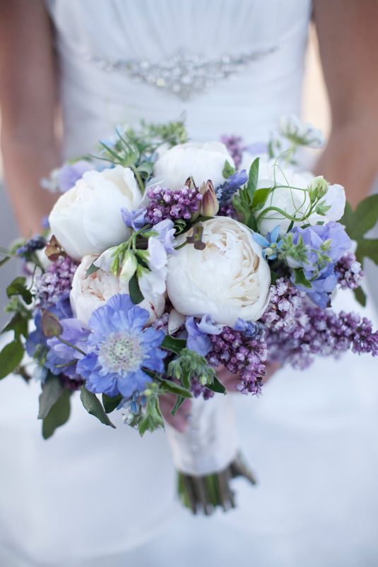 Quinceanera holding a bouquet of white and purple flowers