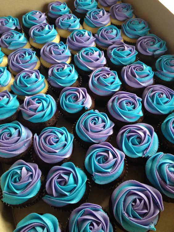 A box of cupcakes with purple and blue frosting, perfect for a Quinceanera celebration