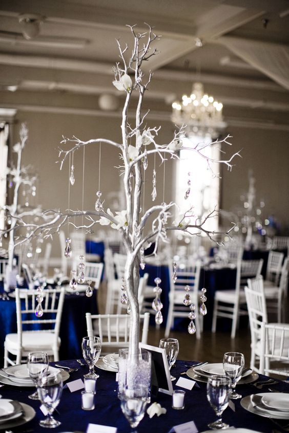 A table set for a Quinceañera reception with navy blue linens and Quinceañera dresses