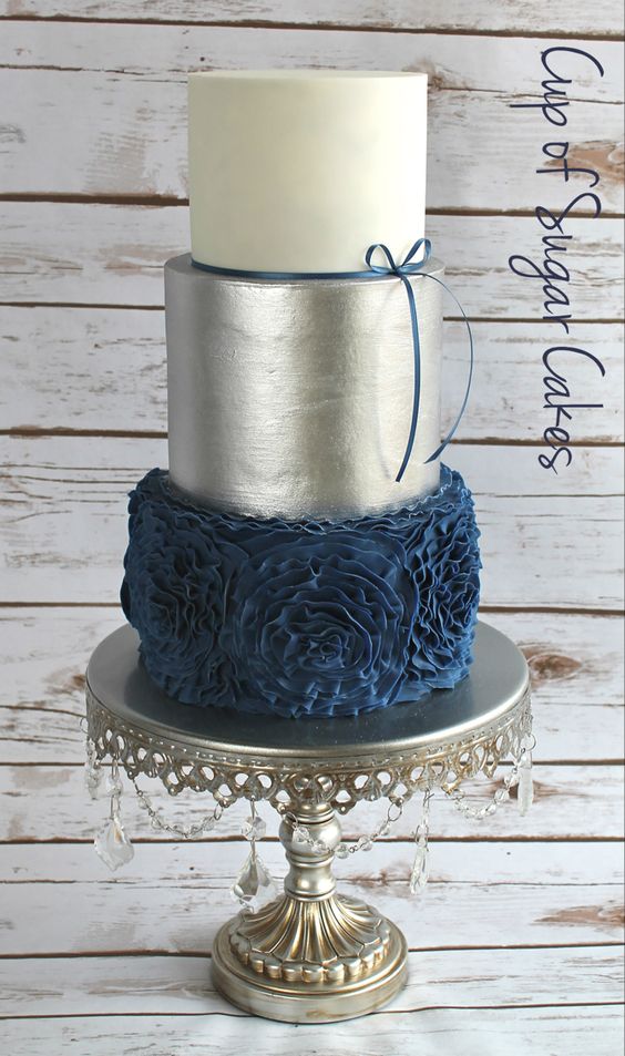 Quinceanera cake, a three tiered cake with blue flowers on a cake stand