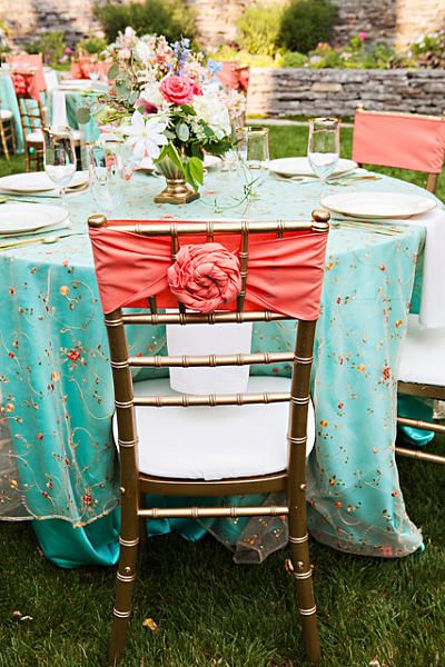 A Quinceanera table decorated with mint and coral colors, featuring a blue and red table cloth.