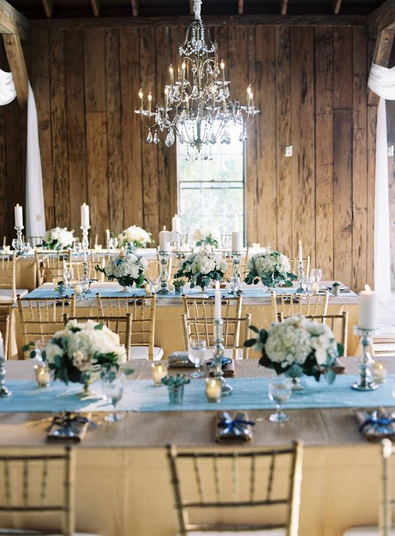 A rustic dusty blue Quinceanera reception with tables and chairs and a chandelier