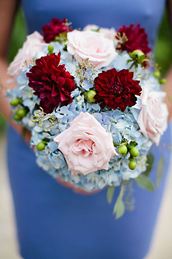 A woman in a blue dress holding a Quinceanera floral bouquet.