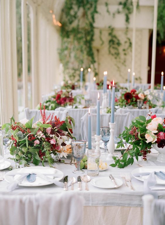 A Quinceanera-themed centrepiece floral design on a table set for a formal dinner with candles and flowers.