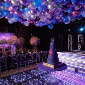 A Quinceanera themed room filled with lots of purple and blue balloons, resembling a galaxy theme