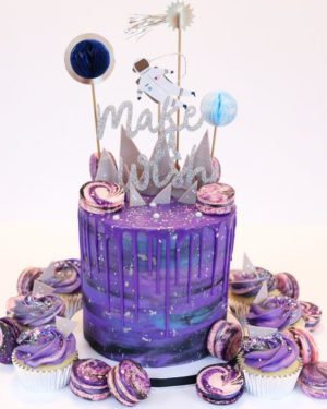 A Quinceanera cake decorated with lilac frosting, featuring cupcakes and cupcake toppers