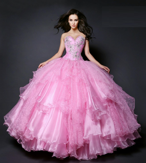 A woman posing for a picture in a pink Quinceañera dress