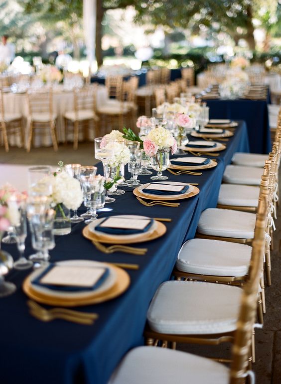 Quinceanera, a long table is set with navy blue and gold plates and glasses