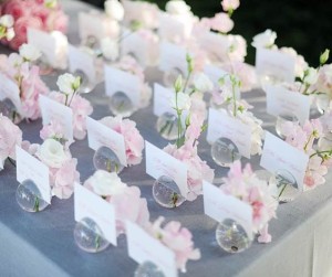 Quinceañera decorations in pink and gray, featuring a table decorated with several small vases filled with flowers