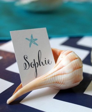 A DIY Quinceanera place card featuring a seashell with a place card on top