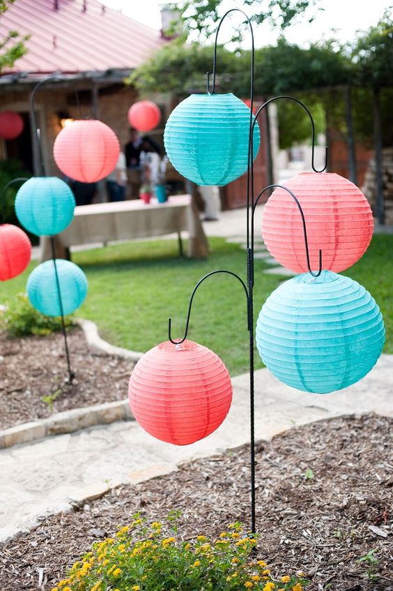 A colorful display of Quinceanera-themed decorations, featuring a balloon lantern and a bunch of paper lanterns hanging from a tree.