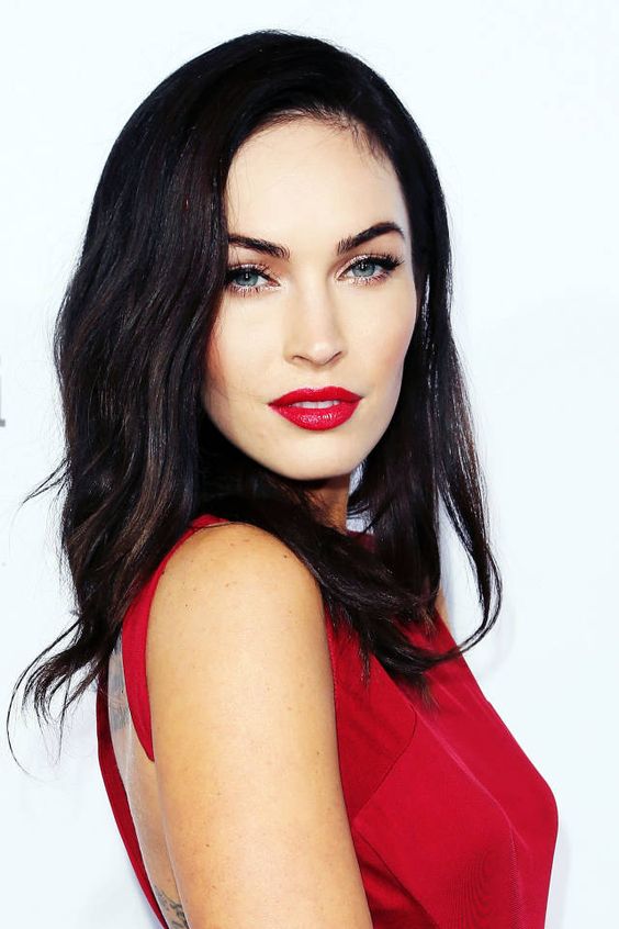 Megan Fox, a woman in a red Quinceanera dress with red lips, posing for a picture