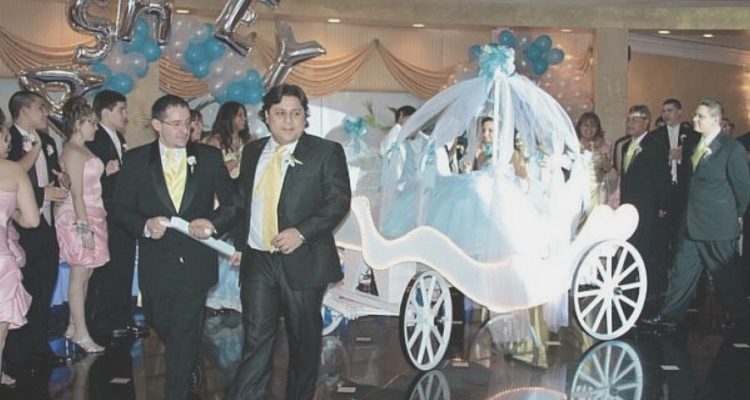 Quinceanera in baby blue dress making her entrance in a coach pulled by two of her chambelanes
