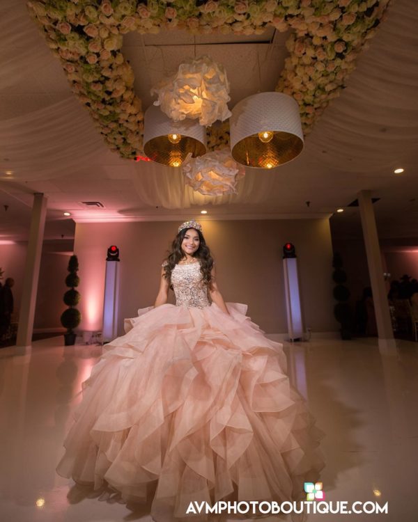 Quinceanera gown, a woman in a Quinceanera dress standing under a chandelier