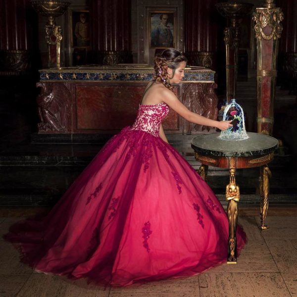 Quinceanera gown Dress, a woman in a red and pink dress standing next to a table