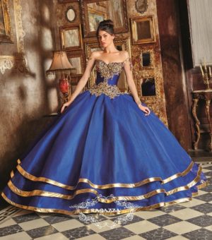 A woman wearing a beauty and the beast quinceanera dress standing in a room.