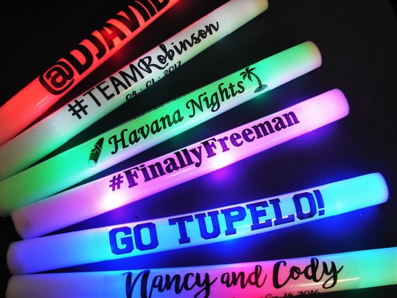 A group of glow sticks with the words 'go tupelo' on them, illuminating the room with neon light at a Quinceanera celebration.