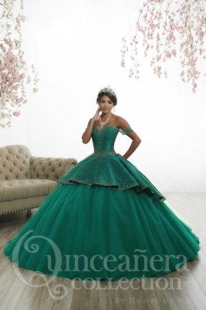 A picture of a woman in a green ball gown posing for a picture. The theme of the Quinceañera is emerald green.
