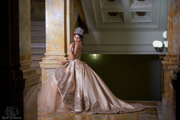 Quinceanera gown - a woman in a dress sitting on a pillar