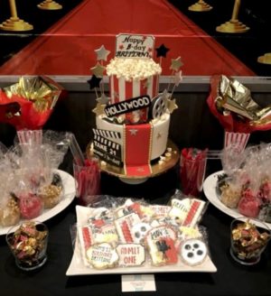 A Quinceanera themed dessert table with a cupcake and a cake covered in cookies