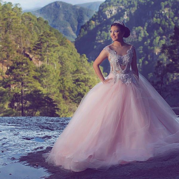 A woman in a Quinceanera gown standing on a rock