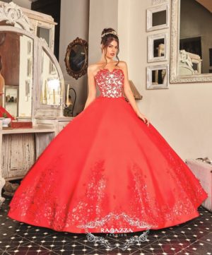 A woman in a red gown standing in front of a mirror wearing Quinceañera dresses