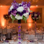 Quinceanera centerpiece ideas purple: A vase with purple and white flowers on a table