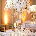 A Quinceanera centrepiece table featuring a tall vase filled with lots of white flowers