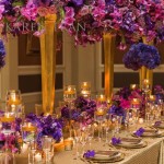 Elegant Quinceanera table with purple and gold table settings. A long table adorned with purple flowers and candles.