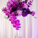 A quinceanera-themed table with a vase filled with purple flowers