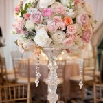 A tall Quinceanera centerpiece featuring a table with a vase of flowers on it