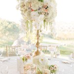 Quinceanera centerpiece featuring pink floral design with a tall vase filled with flowers on a table.