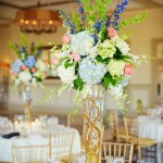 A beautiful Quinceanera centrepiece featuring a tall vase filled with flowers on top of a table