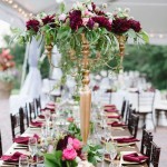Quinceanera decor: a long table with a vase of flowers in berry and gold colors at Oxon Hill Manor