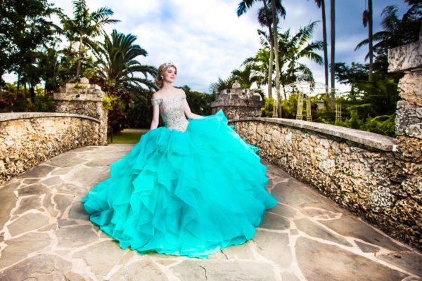 A woman in a blue dress posing for a picture in a Quinceanera event at Secret Gardens Miami.