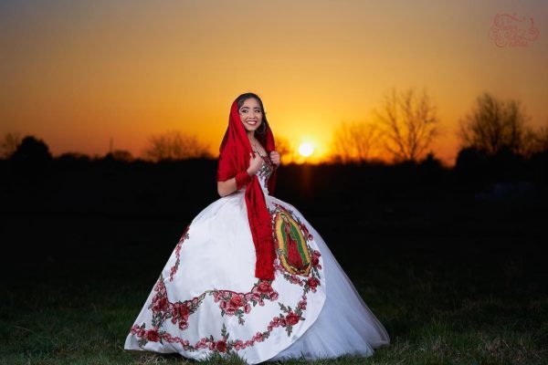 A woman in a Quinceanera gown standing in a field