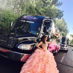 A woman in a pink dress standing in front of a luxury black truck