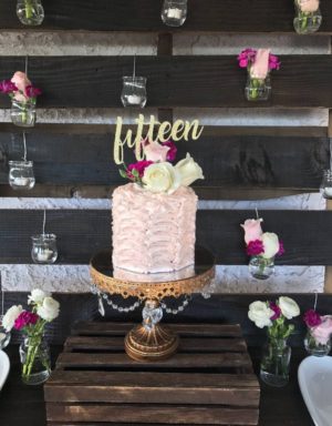 Quinceanera cake, a pink cake sitting on top of a wooden table