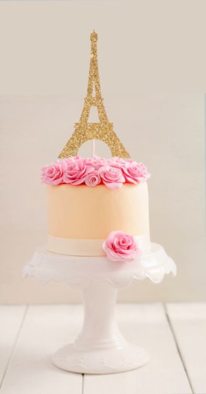 A Quinceanera themed cake with a gold Eiffel Tower decoration on top