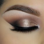 A close up of a woman's eyes with eyeshadow and a makeup brush, perfect for a Quinceanera look.
