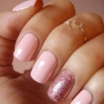 Quinceanera nail design featuring pink gels and a woman's hand with a pink manicure and a gold ring.